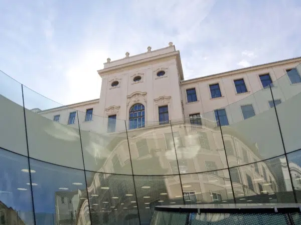 Ihr seht die Fassade des Joanneumsviertels in Graz mit dem historischen Gebäude und dem modernen Glaskegel im Innenhof.