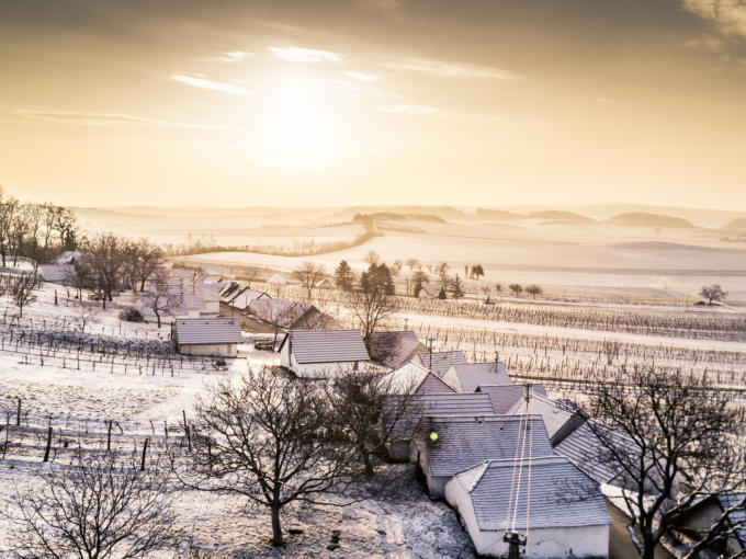 Ihr seht eine verschneite Winterlandschaft in Niederösterreich mit Häusern und Weingärten. Winter Weinviertel Kellergasse