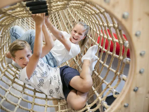 Ihr seht Kinder im Kletternetz im JUFA Hotel Weiz. Der Ort für kinderfreundlichen und erlebnisreichen Urlaub für die ganze Familie.