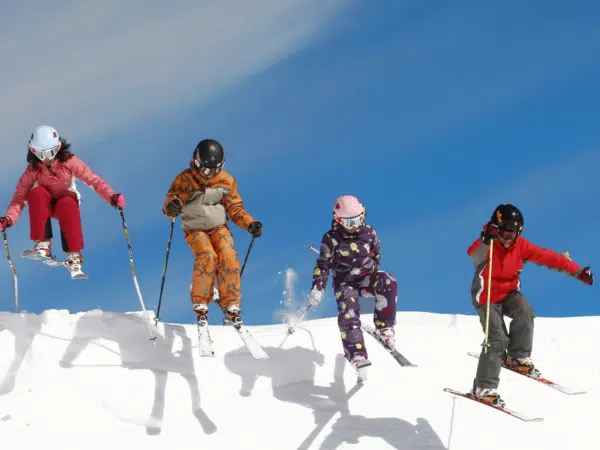 Ihr seht vier Kinder beim Springen beim Skifahren im Winter.