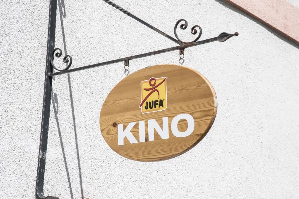 Das Kino-Schild aus Holz an der Außenfassade des JUFA Hotel Murau. Genießt tolles Kinoprogramm mit eurer Familie im JUFA Hotel Murau.