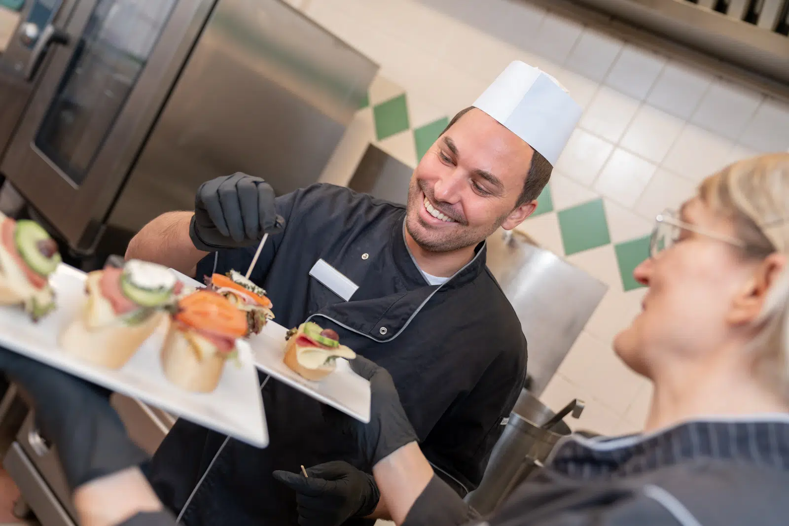 Ihr seht zwei Köche beim Probieren von fertigen Brötchen. JUFA Hotels sind das ganze Jahr der ideale Ort für einen abwechslungsreichen Urlaub für die ganze Familie.