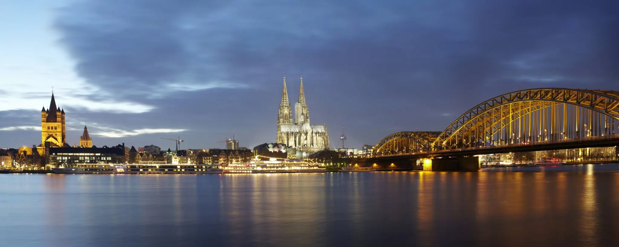 Panorama von Köln mit Rhein, Kölner Dom und Hohenzollernbrücke am Abend. JUFA Hotels bietet kinderfreundlichen und erlebnisreichen Urlaub für die ganze Familie.