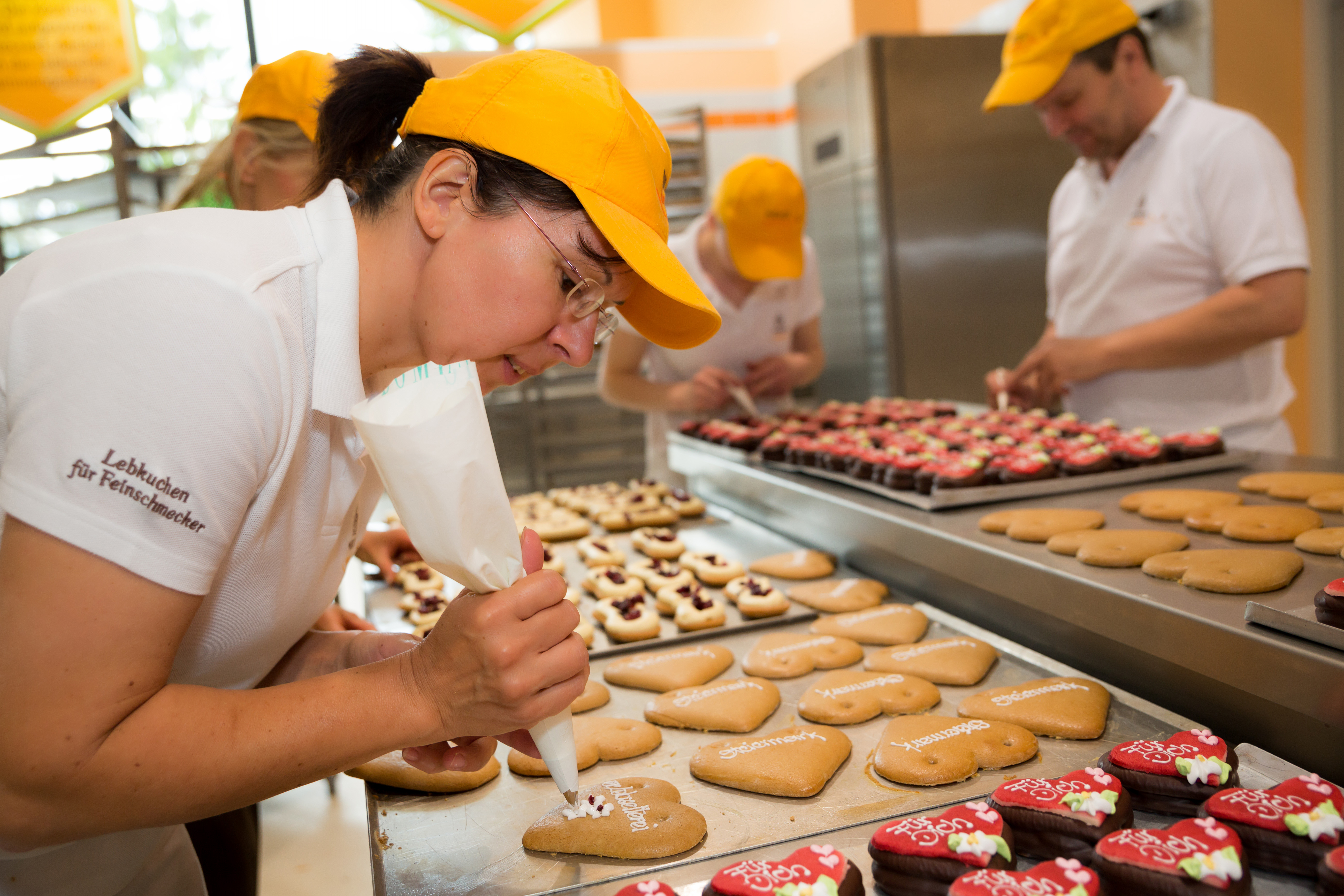 Ihr seht eine Dame beim Lebkuchen verzieren in der Lebkuchenzelterei Pirker in Mariazell. Der Ort für erholsamen Familienurlaub und einen unvergesslichen Winter- und Wanderurlaub.