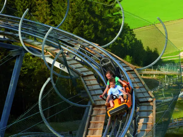 Ihr seht zwei Kinder auf der Sommerrodelbahn auf dem Lucky Flitzer Alpine Coaster.