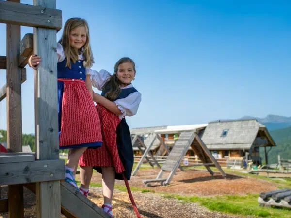 Ihr seht Mädchen im Dirndl am Spielplatz bei der Hiaslhütte in den Nockbergen.