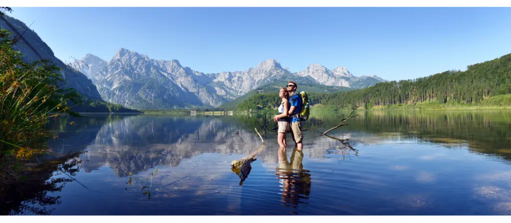 Ein junges Paar steht umarmend im Sommer im Almsee in Oberösterreich. JUFA Hotels bietet Ihnen den Ort für erlebnisreichen Natururlaub für die ganze Familie.