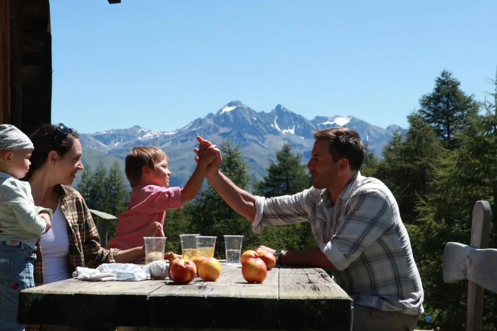 Ihr seht eine Familie, die im Parc Ela in Savognin eine Jause auf der Almhütte geniesst