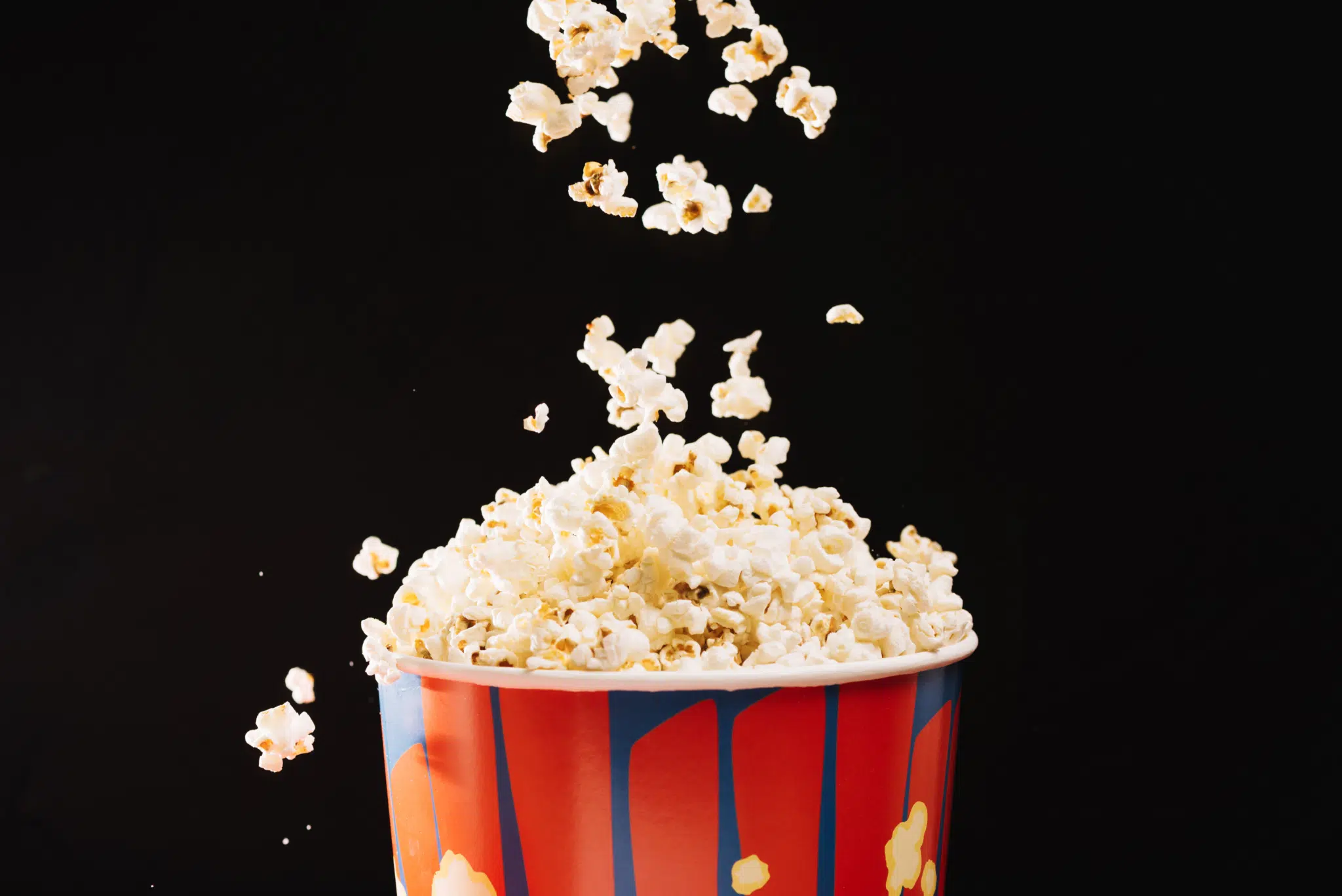 Ihr seht einen Popcornkübel, in den frisches Popcorn hineinfällt.