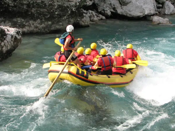 Ihr seht mehrere Menschen in einem Schlauchboot beim Rafting mit viel Action.