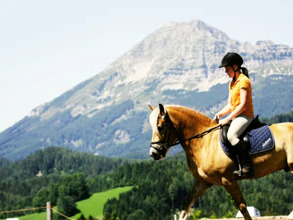 Ihr seht eine Reiterin mit Pferd mit Berg im Hintergrund in Annaberg im Mostviertel. JUFA Hotels bietet Ihnen den Ort für erlebnisreichen Natururlaub für die ganze Familie.