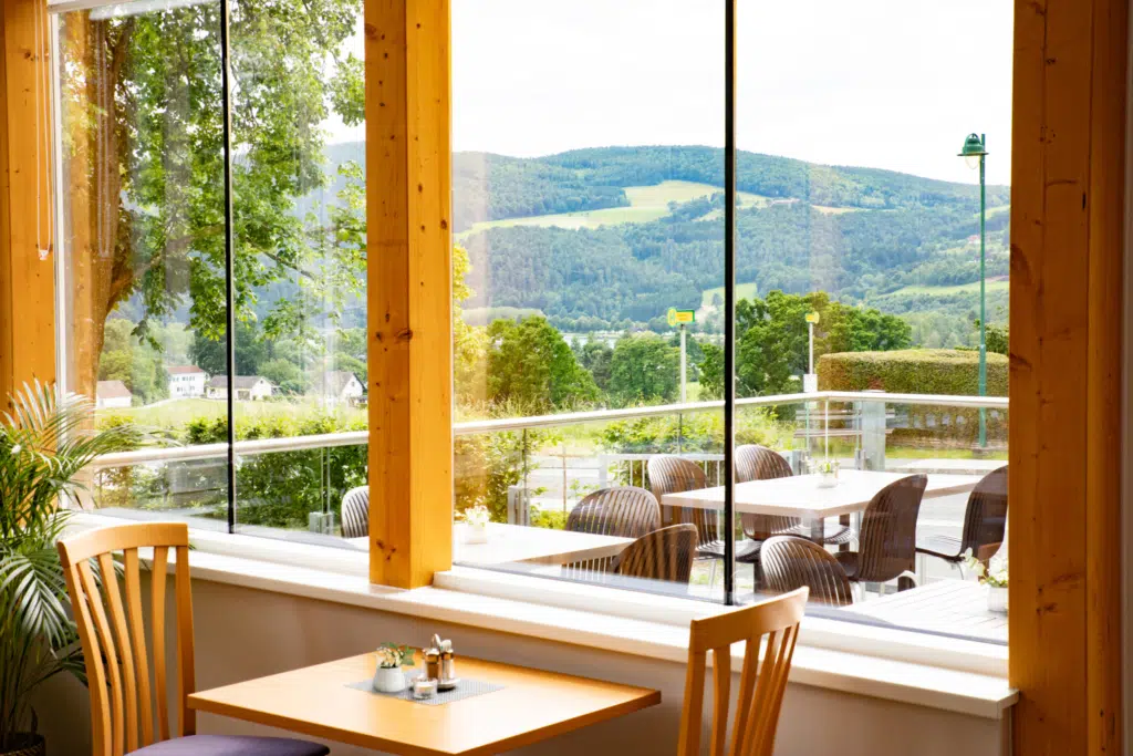 Ihr seht ein Bild vom Wintergarten und der Terrasse mit Tischen & Stühlen im JUFA Hotel Garni Stubenberg in der Oststeiermark.