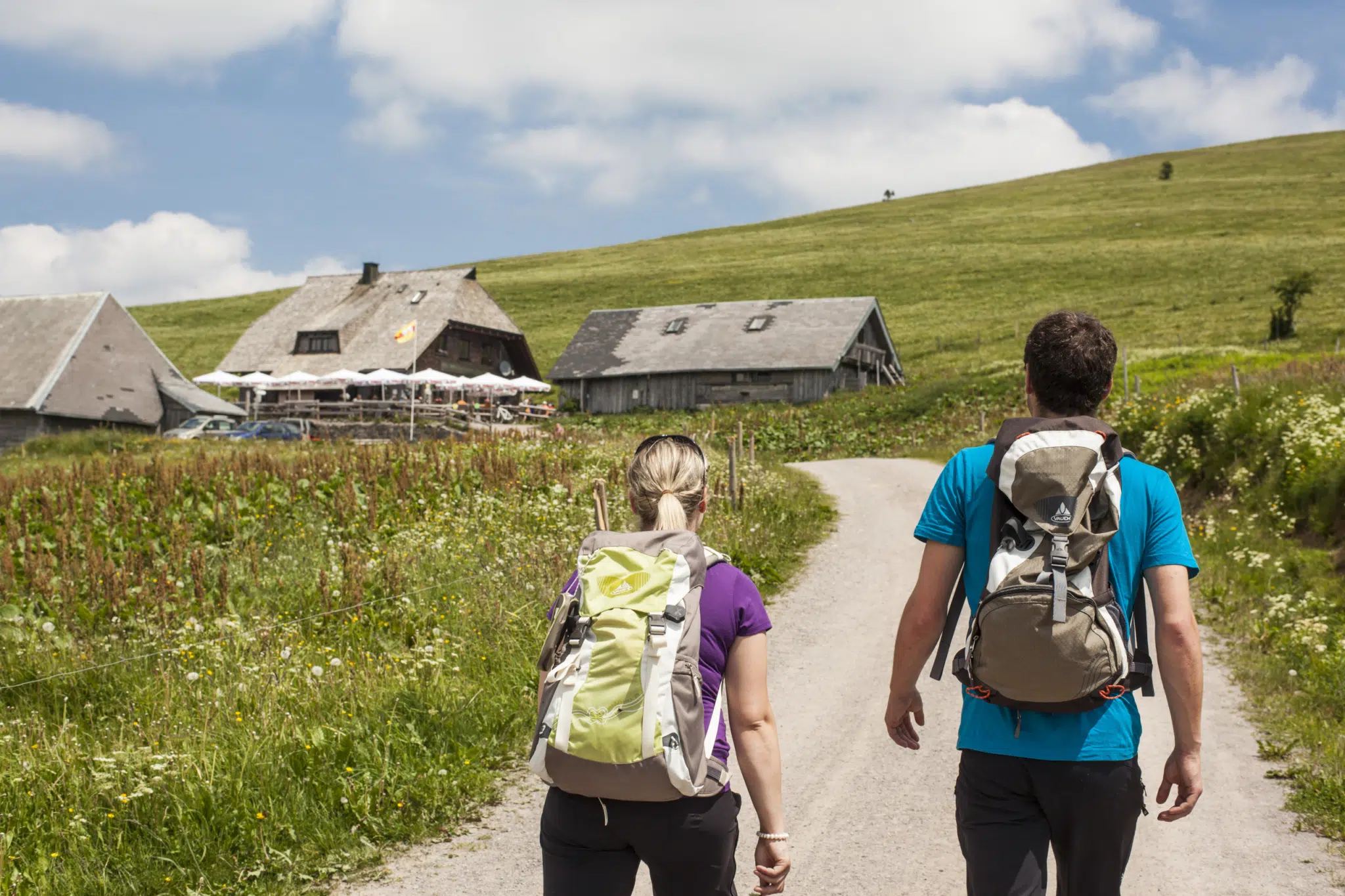 Ihr seht ein Paar, das auf einer Wanderung am Feldberg bei der nächsten Hütte einkehrt. JUFA Hotels bietet Ihnen den Ort für erlebnisreichen Natururlaub für die ganze Familie.