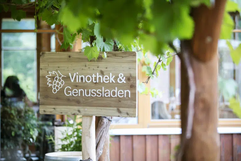 Ihr seht das Schild Vinothek und Genussladen im JUFA Hotel Tieschen – Bio-Landerlebnis. Der Ort für kinderfreundlichen und erlebnisreichen Urlaub für die ganze Familie.