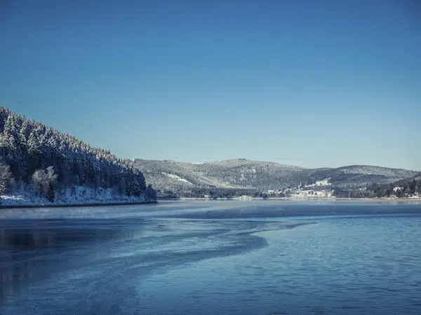 Ihr seht den Schluchsee im Winter mit verschneiter Landschaft.