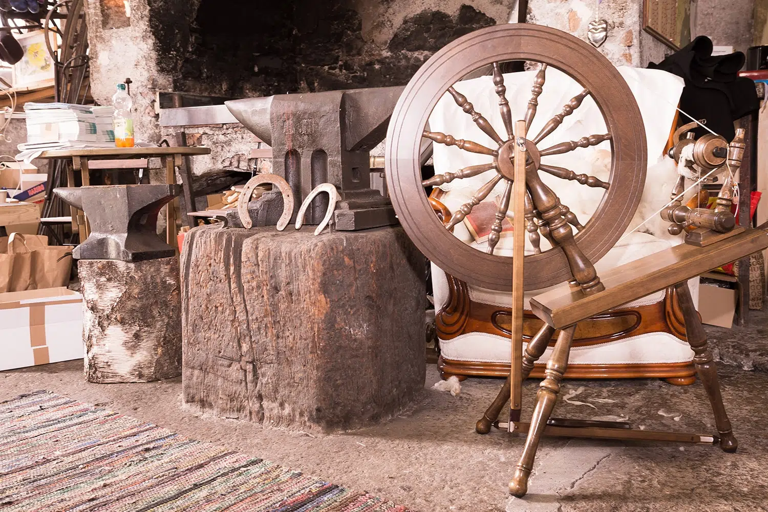 Ihr seht den Ausstellungsraum mit Spinnrad, Amboss und Hufeisen im Schmiedemuseum Weissbriach im Gitschtal.