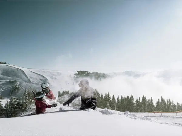 Ihr seht spielende Kinder im Schnee mit Schneeschuhen und Berge im Hintergrund auf der Schmitten