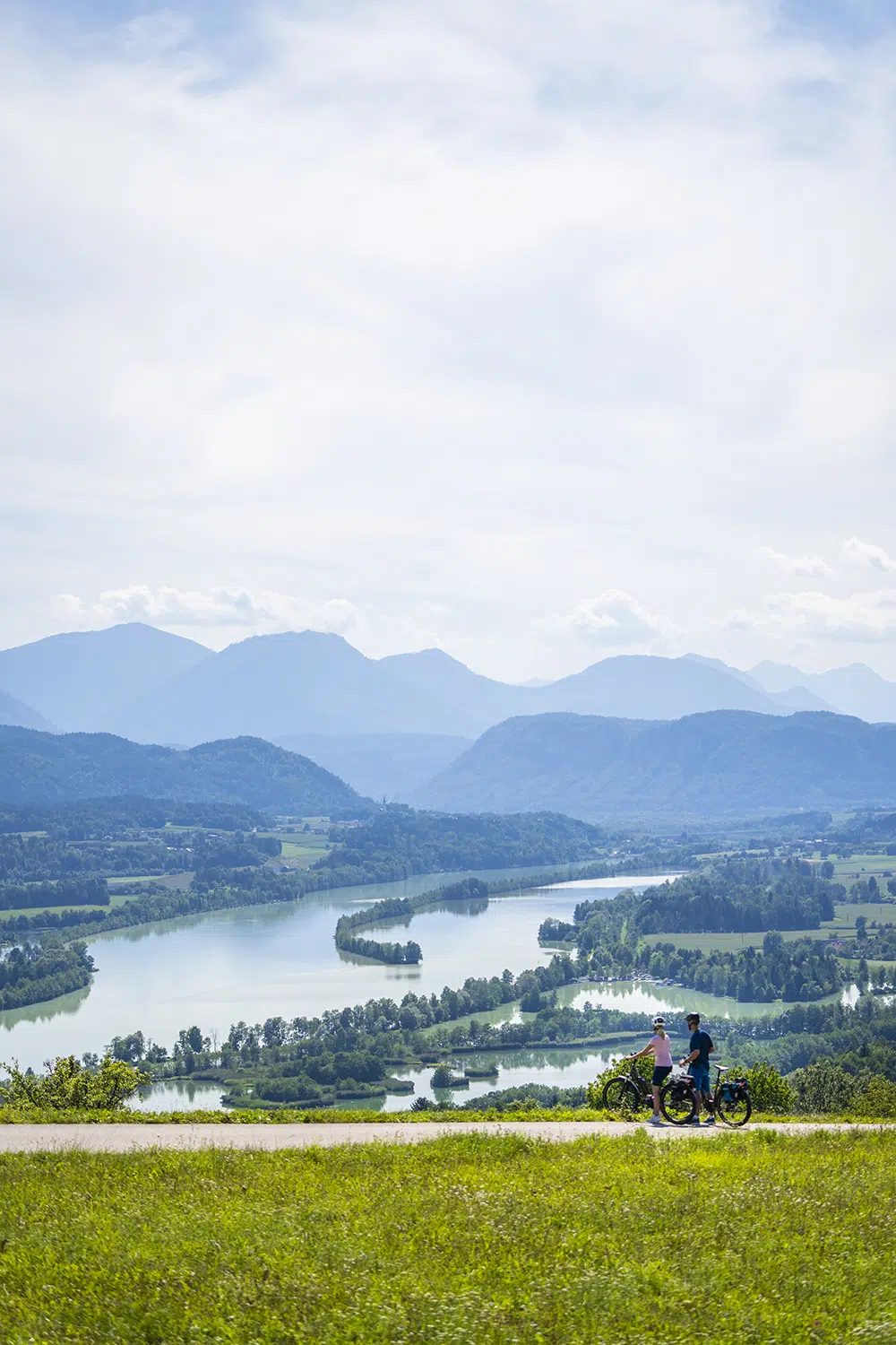 Ihr seht zwei Personen mit ihren Fahrrädern bei der Seenschleife am Klopeiner See in Südkärnten stehen.