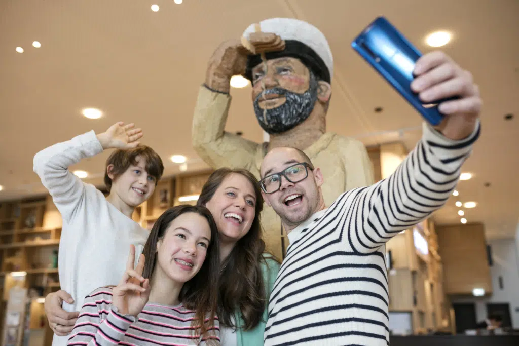 Sie sehen eine Familie beim Selfie machen mit dem Matrosen im JUFA Hotel Hamburg HafenCity. Der Ort für kinderfreundlichen und erlebnisreichen Urlaub für die ganze Familie.