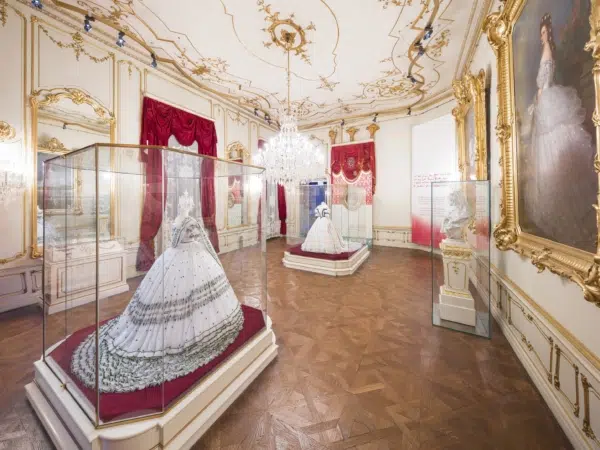 Ihr seht zwei prachtvolle Kleider in Vitrinen im Sisi Museum in der Hofburg Wien.