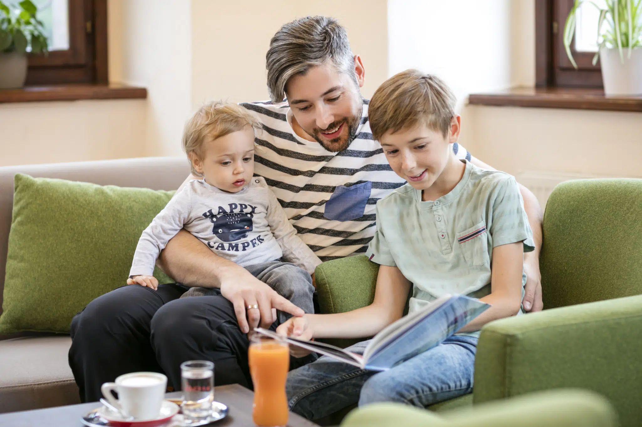 Sie sehen einen Vater mit seinen beiden Kindern in der Lobby des JUFA Hotel Schloss Röthelstein/Admont*** sitzen. Der Ort für märchenhafte Hochzeiten und erfolgreiche und kreative Seminare.