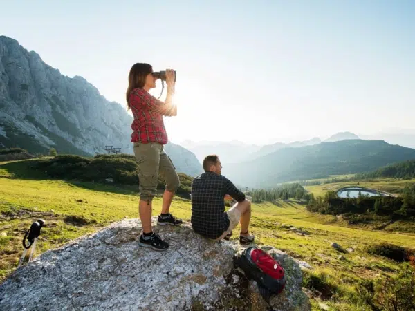 Ihr seht zwei Personen beim Wandern, das gerade eine Pause macht im Wandergebiet Nassfeld in Kärnten im Sommer.