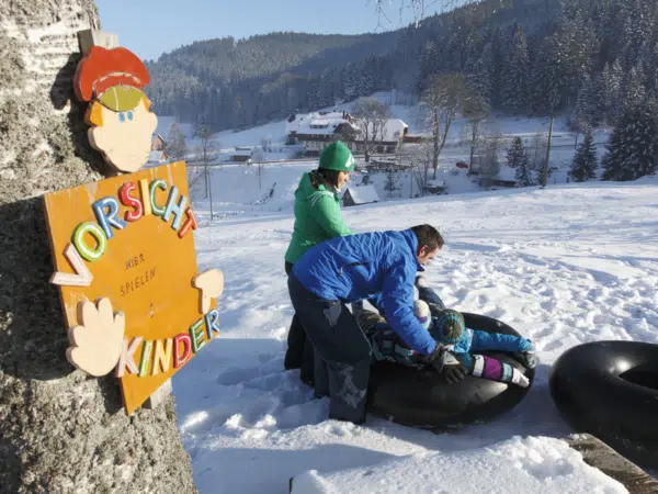 Ihr seht eine Familie beim Snowtubing im Schwarzwald.