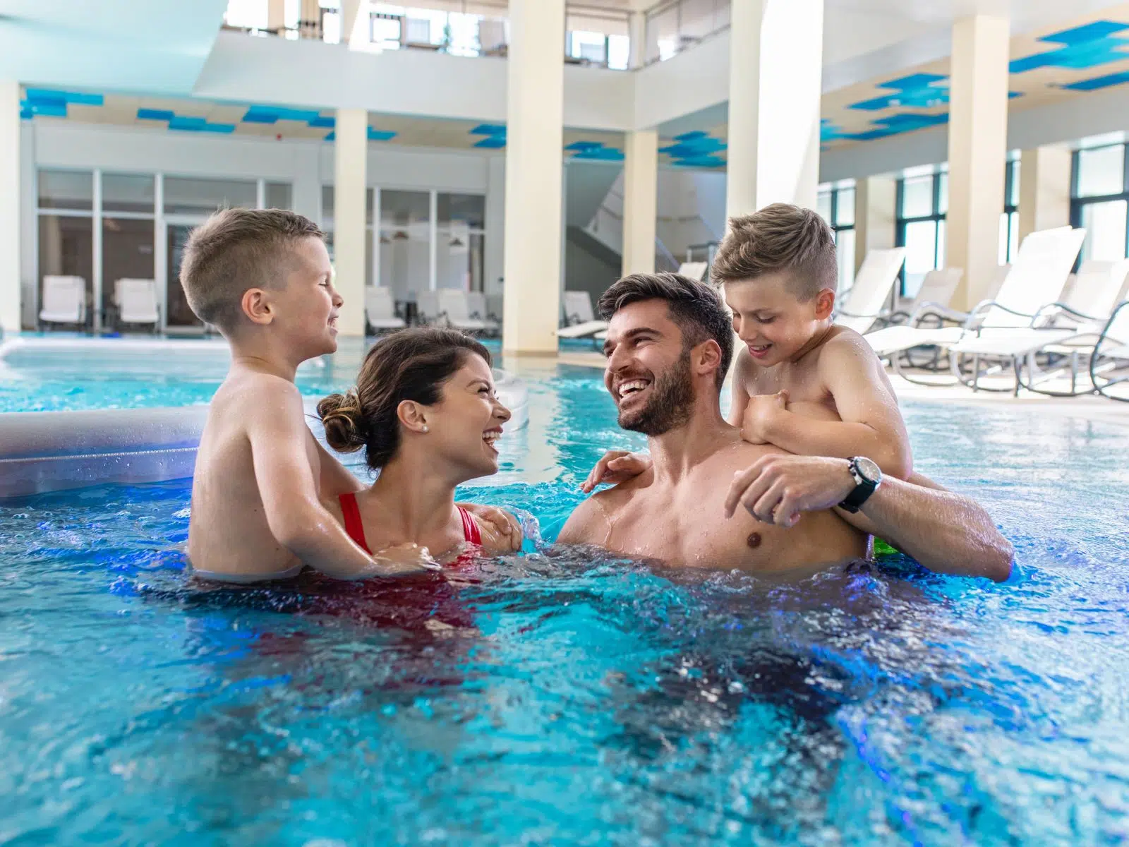 Ihr seht eine Familie mit Kindern beim Baden und Entspannen im Innenbereich einer Therme in der Nähe von JUFA Hotels.