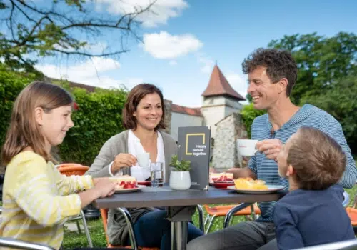 Ihr seht eine Familie in Nördlingen im Garten frühstücken.