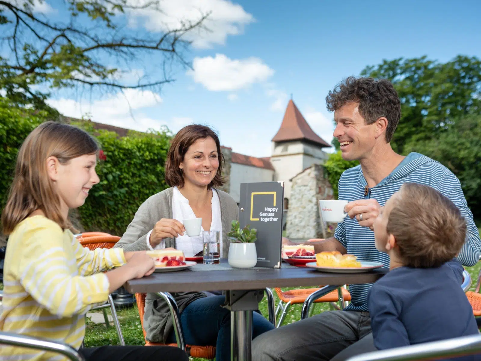 Ihr seht eine Familie in Nördlingen im Garten frühstücken.