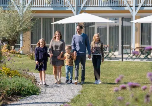 Ihr seht eine Familie, die im Garten eines JUFA Hotels spaziert.