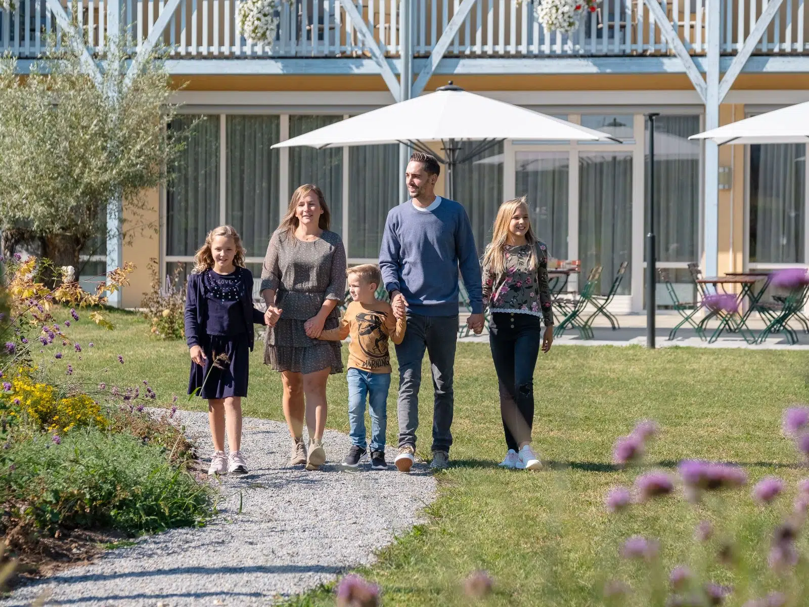 Ihr seht eine Familie, die im Garten eines JUFA Hotels spaziert.