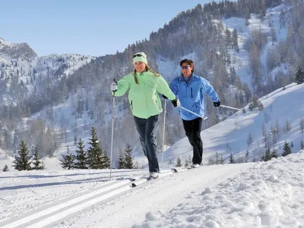 Ihr seht zwei Personen beim Langlaufen im Winter in der Urlaubsregion Pyhrn-Priel.