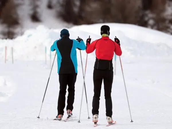 Ihr seht zwei Personen beim Langlaufen im Winter.