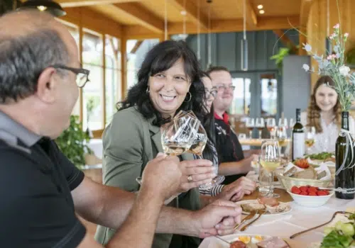 Ihr seht eine Familie beim Wein trinken und jausnen.