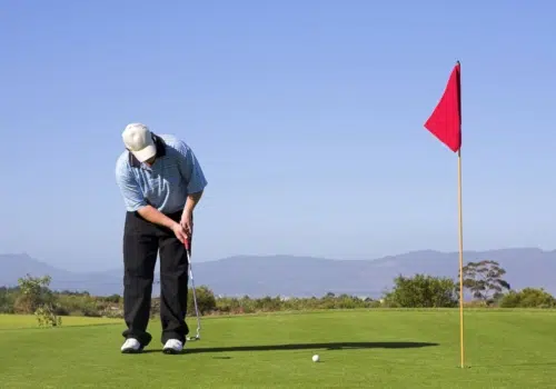 Ihr seht einen Mann beim Golfen im Sommer auf einem Golfplatz.