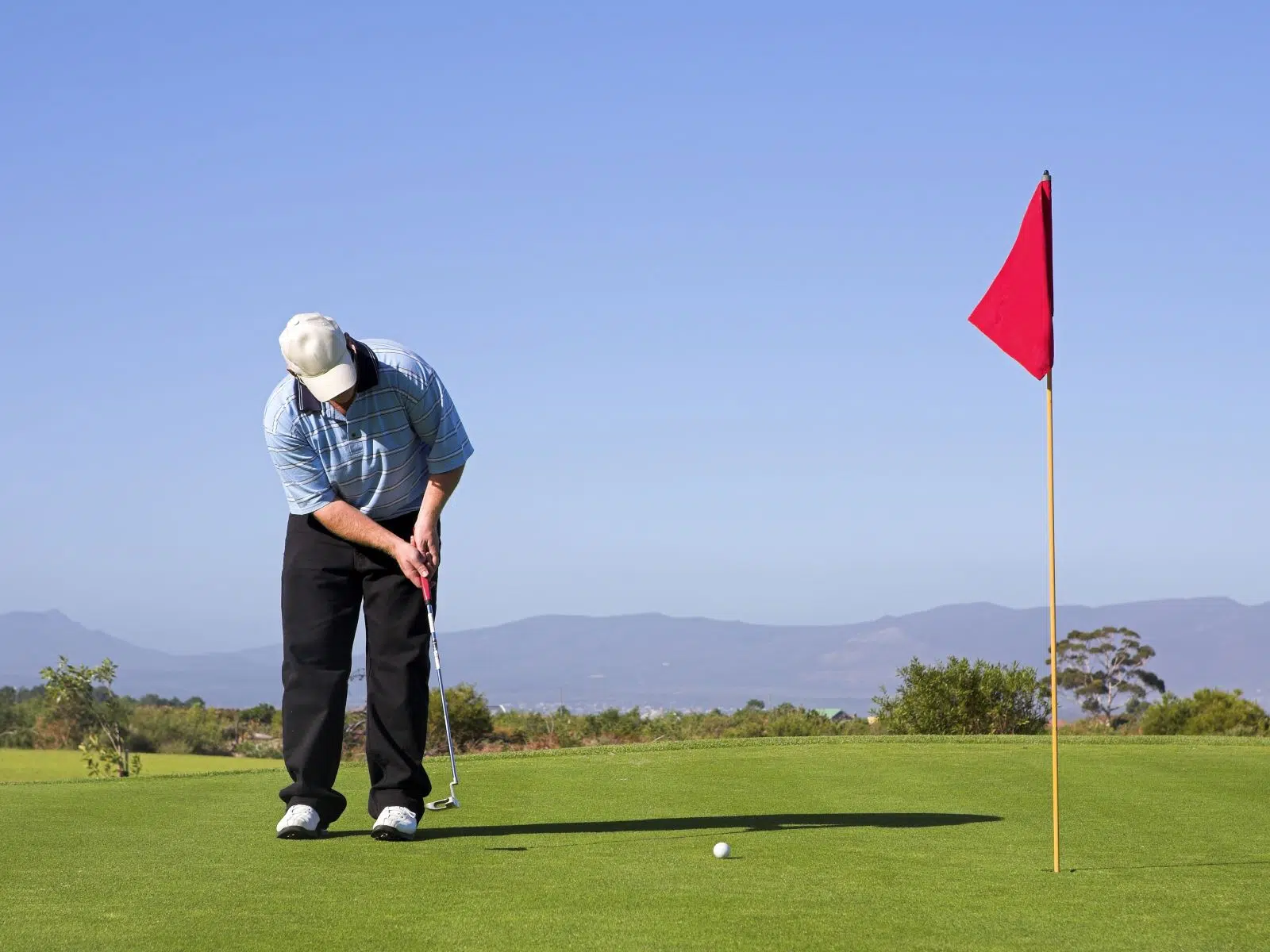 Ihr seht einen Mann beim Golfen im Sommer auf einem Golfplatz.