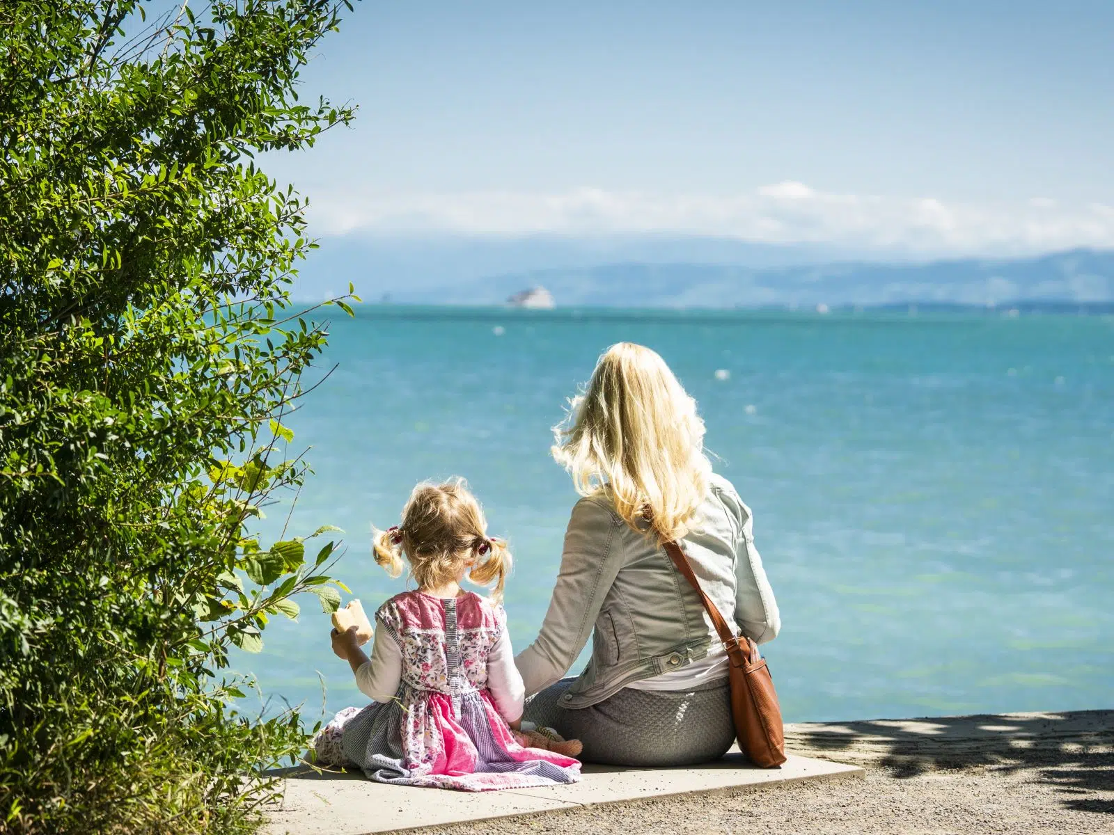 Ihr seht eine Mutter mit ihrem Kind am Bodensee.