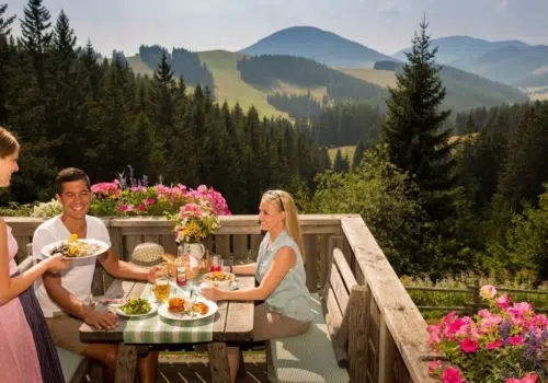 Ihr seht ein Pärchen das Rast auf der Weizerhütte im Almenland macht und das exzellente Speisenangebot genießt.