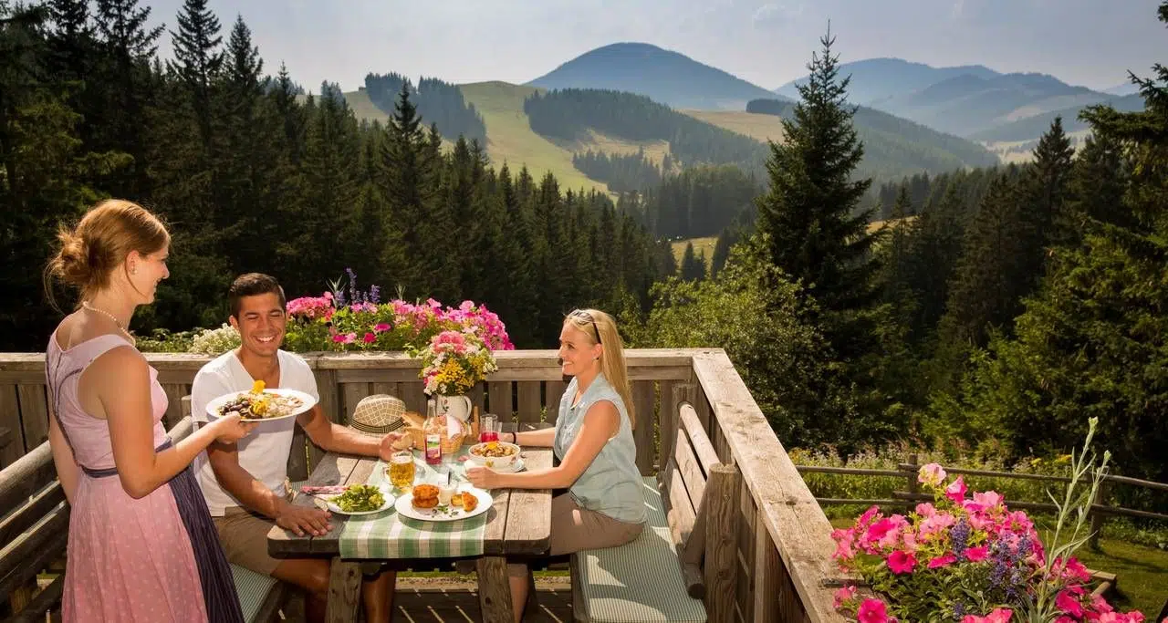 Ihr seht ein Pärchen das Rast auf der Weizerhütte im Almenland macht und das exzellente Speisenangebot genießt.