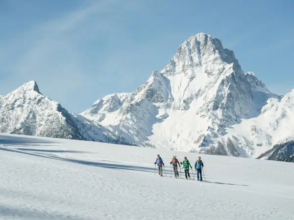 Ihr seht eine Gruppe von Personen beim Schneeschuhwandern im Winter in der Urlaubsregion Pyhrn-Priel.