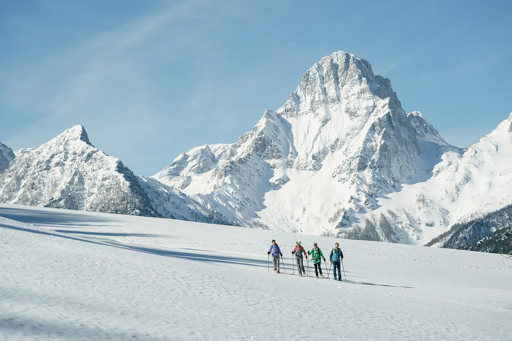 Ihr seht eine Gruppe von Personen beim Schneeschuhwandern im Winter in der Urlaubsregion Pyhrn-Priel.