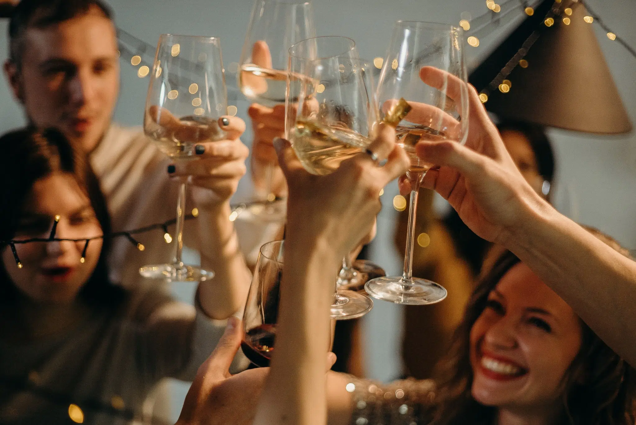 Ihr seht eine Gruppe von Personen, beim Anstoßen mit Sektgläsern, um gemeinsam Silvester zu feiern.