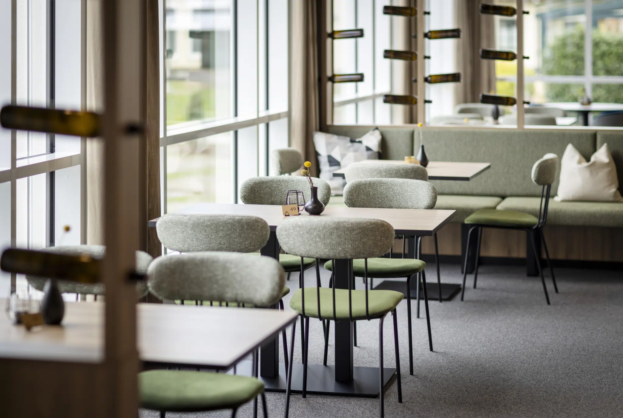 Sie sehen von Tageslicht durchflutete und stilvolle Tische im Restaurantbereich im Café & Restaurant Wandelhalle. Dank den großen Panoramafenstern bekommen hier alle die benötigte Portion Tageslicht.