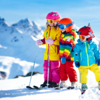 Ihr seht drei Kinder auf Skiern stehend am verschneiten Berg