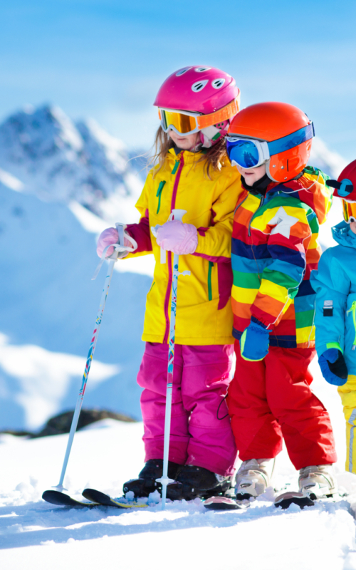 Ihr seht drei Kinder auf Skiern stehend am verschneiten Berg