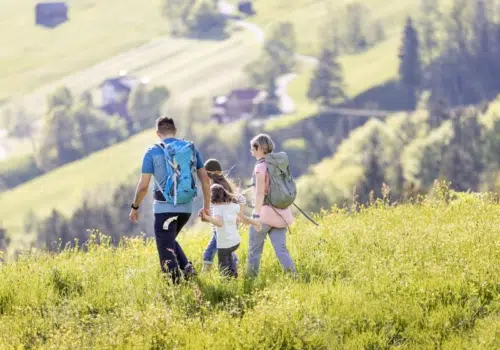 Ihr seht eine Familie beim Wandern im Laternsertal im JUFA Hotel Laterns – Klangholzhus***. Der Ort für erholsamen Familienurlaub und einen unvergesslichen Winter- und Wanderurlaub.