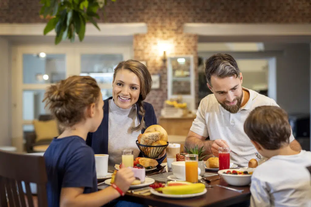 Ihr seht eine Familie am Frühstückstisch mit Mama, Papa, Tochter und Sohn. JUFA Hotels bietet erholsamen Familienurlaub und einen unvergesslichen Winter- und Wanderurlaub.