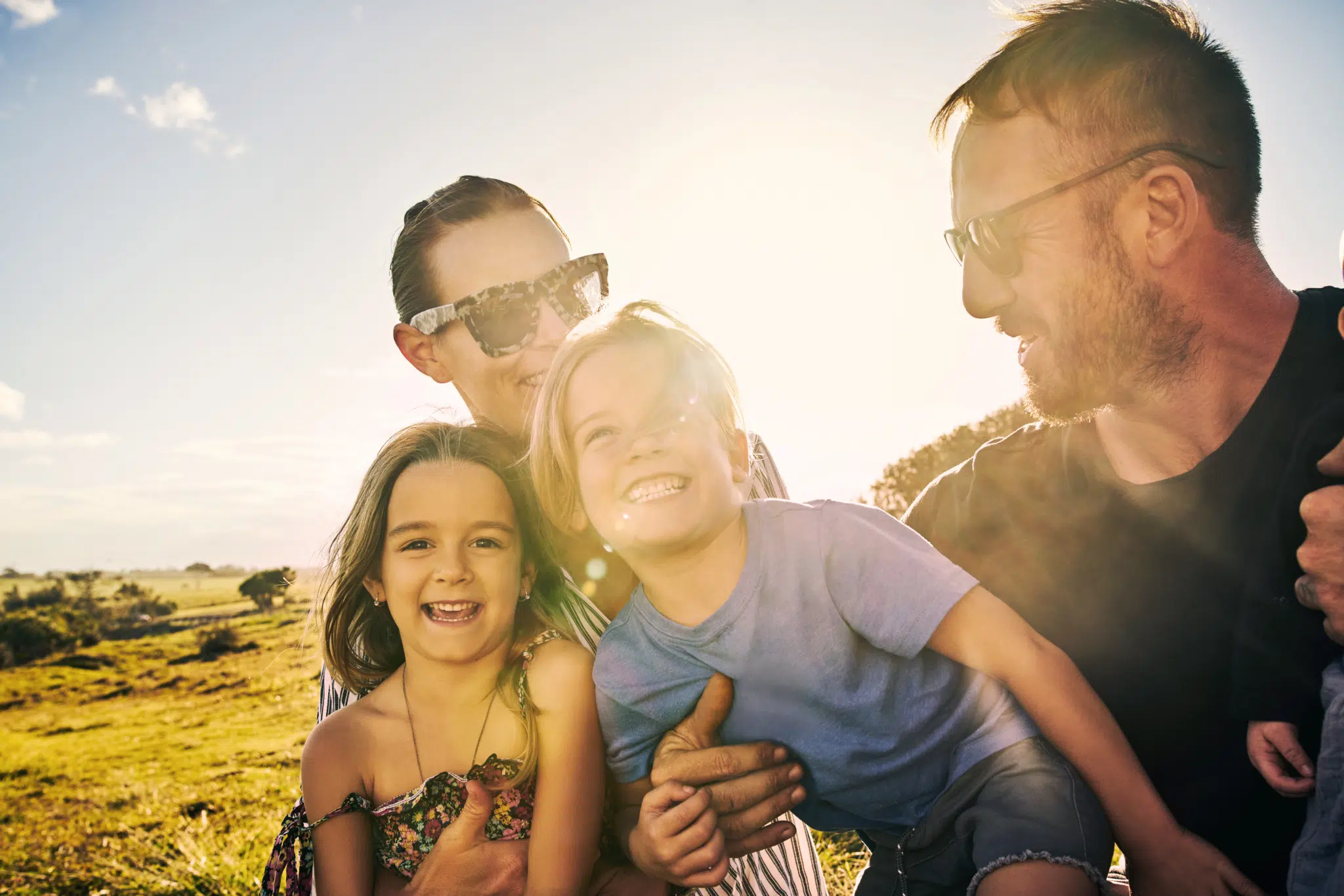 Ihr seht eine Aufnahme einer glücklichen Familie, die im Freien zusammenhält.