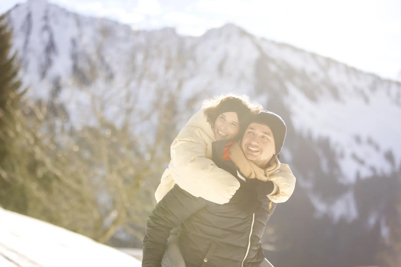 Ihr seht ein junges Paar im Schnee in den Bergen. Das JUFA Hotel Laterns - Klangholzhus ist der perfekte Ort für einen abwechslungsreichen Familienurlaub und unvergessliche Tage im Winter mit der ganzen Familie.